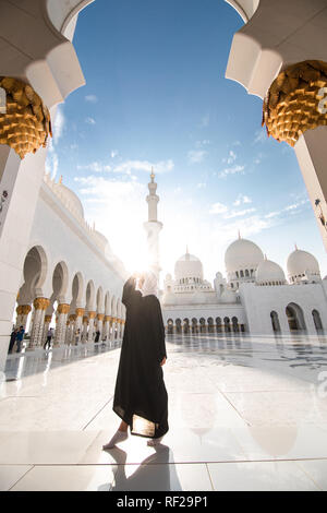 Traditionell gekleidete arabische Frau mit schwarzen Burka wisiting Sheikh Zayed Moschee in Abu Dhabi, Vereinigte Arabische Emirate. Stockfoto
