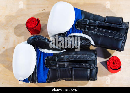 Zwei schwarze, blaue und weiße Boxhandschuhe auf hellen Hintergrund Stockfoto
