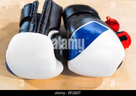 Zwei schwarze, blaue und weiße Boxhandschuhe auf hellen Hintergrund Stockfoto