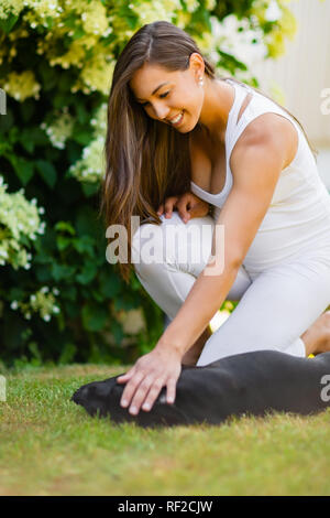 Gerne schwangere Frau mit einem großen Bauch streichelt ihr Hund im Garten Stockfoto