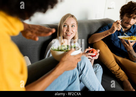 Freunde sitzen auf der Couch Sprechen und Essen Stockfoto