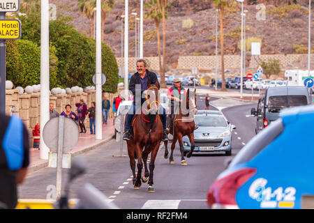 Zwei Reiter reiten ihre Pferde durch den Verkehr auf der Straße in San Sebastian Fiesta in La Caleta, Teneriffa, Kanarische Inseln, Spanien Stockfoto