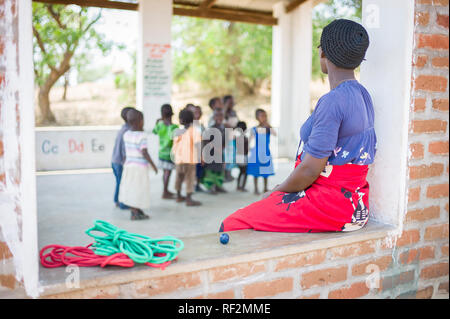 Ein Lehrer wacht über ihre Klasse der jungen Kinder in einer ländlichen, offene Schule Zimmer in der Nähe von Chikwawa, Malawi. Stockfoto