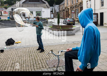 Jugend in Blau hoody Freiwillige für Street Performer mit großen Blasen zeigen, Fort William Stadtzentrum highlands Schottland Großbritannien Stockfoto