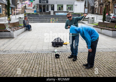 Jugend in Blau hoody Freiwillige für Street Performer mit großen Blasen zeigen, Fort William Stadtzentrum highlands Schottland Großbritannien Stockfoto