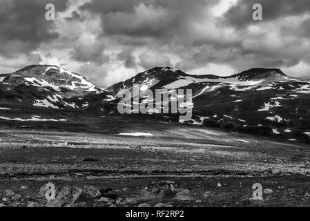 Ein Blick auf die felsigen und steinigen Gelände mit stürmischen Wolken mit Bergen im Hintergrund. Norwegen, um Beitostolen. Stockfoto