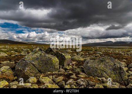 Ein Blick auf die felsigen und steinigen Gelände mit stürmischen Wolken mit Bergen im Hintergrund. Norwegen, um Beitostolen. Stockfoto