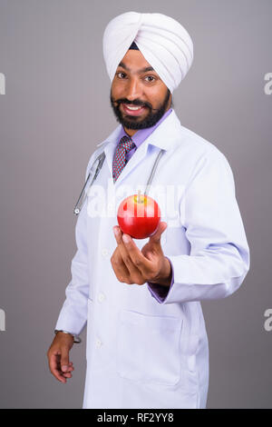 Junge indische Sikh mann Arzt und lächelnd Apple Stockfoto