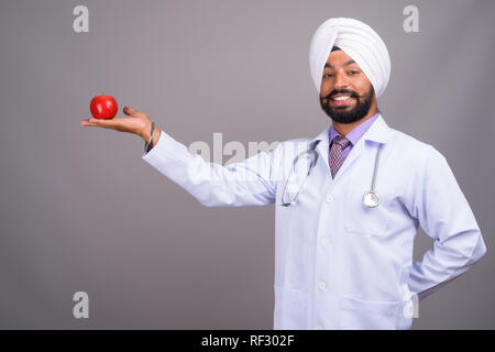 Junge indische Sikh mann Arzt und lächelnd Apple Stockfoto