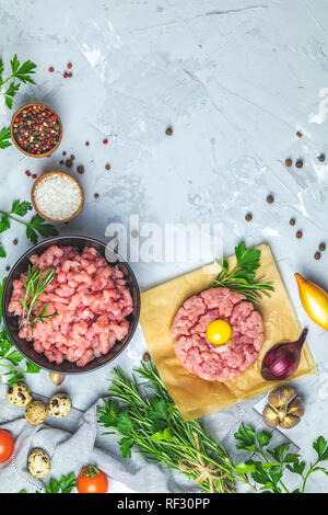 Gesundes Essen, kochen Konzept. Hausgemachte organischen Fleisch Hackfleisch und Tatar mit Eigelb mit Gemüse auf hellen grauen Stein Beton texturiert Stockfoto