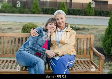 Portrait der älteren Frau sitzen zusammen mit ihrer erwachsenen Tochter auf einer Bank Stockfoto