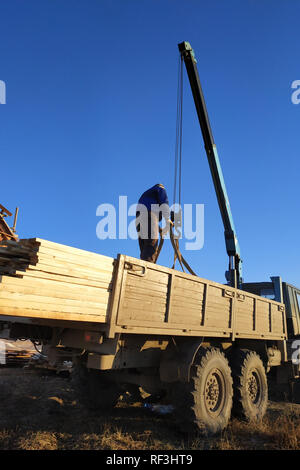 Entladen Boards von der Seite der Kran mit der Hilfe von Menschen, 2019 Stockfoto