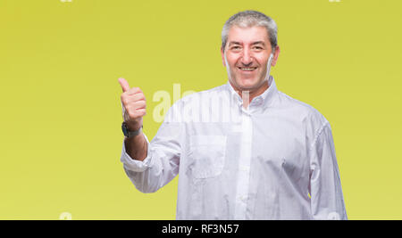 Gut aussehender älterer Mann über isolierte Hintergrund lächelnd mit glücklichen Gesicht und zeigt auf die Seite mit dem Daumen nach oben. Stockfoto