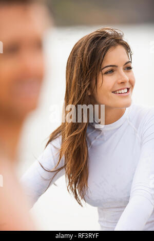 Junge Frau am Strand, mit ihrem Freund im Vordergrund, unscharf. Stockfoto