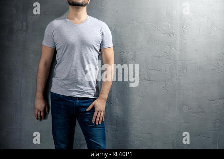 Gesunde junge Mann mit grauen T-Shirt auf konkreten Hintergrund mit Copyspace für Ihren Text. Bild ohne Modell. Stockfoto