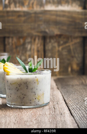 Mango Bananen Smoothie in Glas, gesunden Dessert mit natürlichen griechischer Joghurt und Chia Samen, vegetarisches Frühstück mit Honig auf hölzernen ländlichen Tabelle, Clos Stockfoto