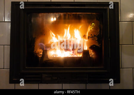 Ein Brennen in einem Holzofen log liefert Wärme für den Raum. Stockfoto