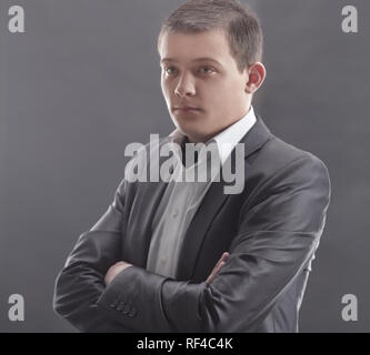 Stilvolle junger Mann in einem grauen Anzug. Isolierte auf Grau Stockfoto