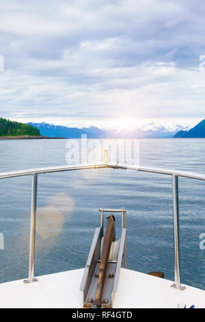 Motor Crusing Yacht in der Glacier Bay National Park, Alaska. Sonnenuntergang Blick auf fernen Inseln und die schneebedeckten Berge der Bogen ein Motorboot. Stockfoto