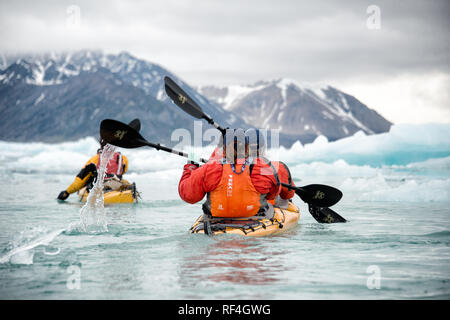 SVALBARD, Norwegen - Kajaktouristen erkunden das eisige Wasser und die unberührten Landschaften der Arktis rund um Svalbard. Diese einzigartige und abenteuerliche Form des Tourismus bietet ein Erlebnis aus nächster Nähe mit der arktischen Umgebung und zeigt die atemberaubende Schönheit und empfindliche Ökosysteme der Region. Stockfoto