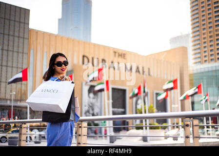 Dubai, Vereinigte Arabische Emirate - 26. März 2018: asiatische Touristen vor Dubai Mall Haupteingang mit Tüten Stockfoto
