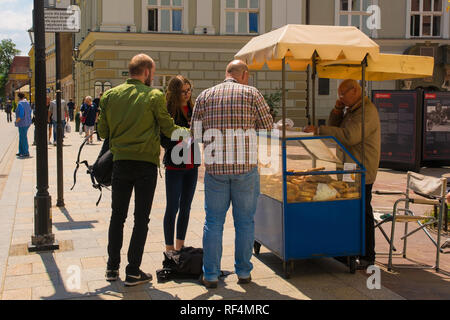 Krakau, Polen - 13. Juli 2018. Ein Anbieter verkauft Obwarzanek Krakowski aus seinem Stall auf Grodzka Ulica. Das ist ein traditionelles Straße Snack - Geflochtene rin Stockfoto