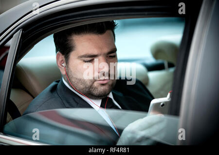 Unternehmer im Taxi Musik auf sein Handy Stockfoto