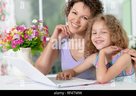 Süße kleine Mädchen mit junge Mutter mit Laptop Stockfoto