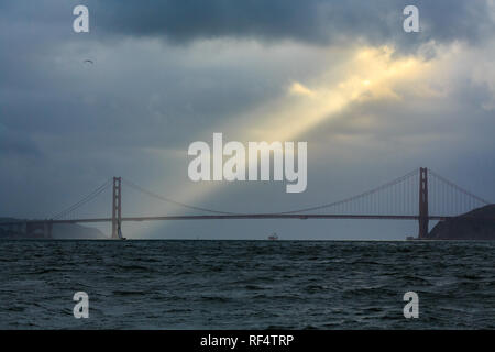 Ray der goldene Sonne leuchtet nach unten durch die Wolken über auf die Golden Gate Bridge und der San Francisco Bay Stockfoto