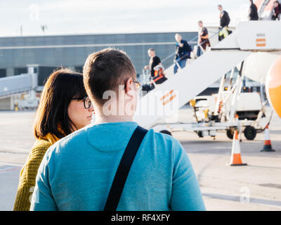 BASEL, SCHWEIZ - Nov 11, 2018: Rückansicht von Mann und Frau sprechen, in der Nähe der EasyJet Airbus A 320-214 OE-IJR Ebene auf Asphalt mit Passagieren in absteigender Reihenfolge von vorne fahren Sie an einem sonnigen Tag Stockfoto