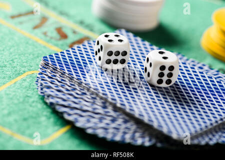 Selektiver Fokus der Würfel auf die Karten im Deck mit Chips und grün Pokertisch auf Hintergrund Stockfoto