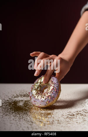 7/8-Ansicht von Frau mit Donut mit glänzenden funkelt in Hand isoliert auf Schwarz Stockfoto