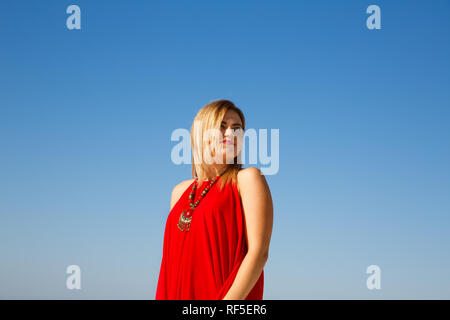 Blonde Frau mit Halskette im roten Kleid. Stockfoto