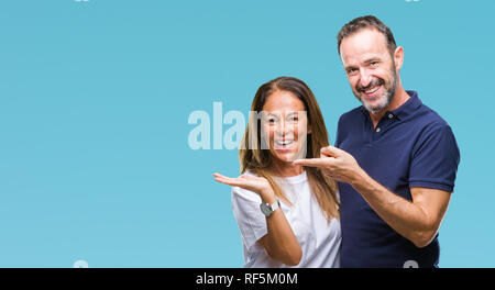 Mittleres Alter spanischer casual Paar über isolierte Hintergrund erstaunt und lächelt in die Kamera während der Präsentation mit Hand und zeigte mit dem Finger. Stockfoto