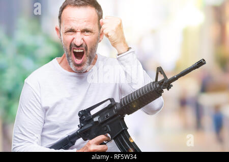 Mittleres Alter senior hoary kriminellen Mann mit Pistole Waffe über isolierte Hintergrund genervt und frustriert schrie mit Zorn, verrückt und schreien mit Ra Stockfoto