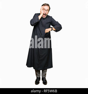 Mittleres Alter Mann, der katholische Priester robe schaut auf die Uhr Zeit Sorgen, Angst, sich spät Stockfoto