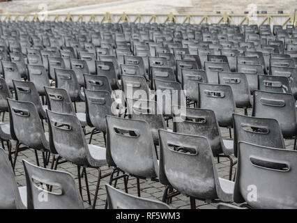 Selektiver Fokus vieler grauen Stühlen in geraden Linien auf einem gepflasterten Platz. Stockfoto