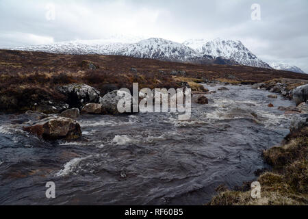 Der Fluss Etive mit den schneebedeckten Gipfeln der Schottischen Highlands im Hintergrund, Glencoe, Schottland, Vereinigtes Königreich. Stockfoto