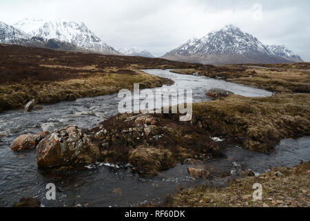 Der Fluss Buachaille Etive mit Etive Mor und schneebedeckten Gipfeln der Schottischen Highlands im Hintergrund, Glencoe, Schottland, Vereinigtes Königreich. Stockfoto