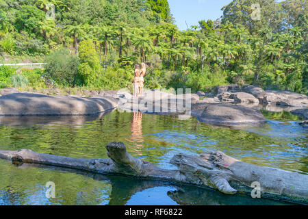 TAURANGA NEUSEELAND - 23. Januar 2019; gebräunte Paar ständigen Bach auf in Wasserloch widerspiegelt und malerische Wasserfälle auf heißen Sommertag an Stockfoto