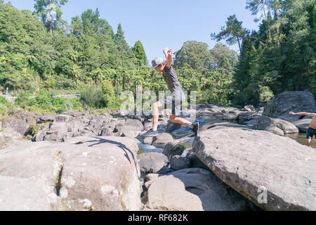 TAURANGA NEUSEELAND - 23. Januar 2019; malerische Wasserlöcher und Wasserfälle mit Junge in motion in Schatten springen auf Felsen und Menschen verwischt genießen Stockfoto