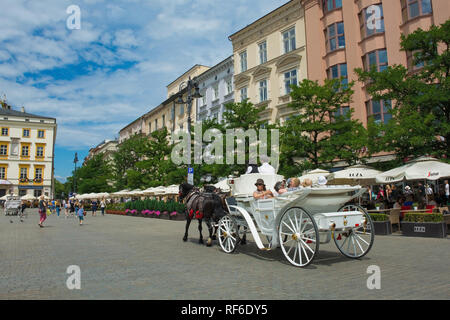 Krakau, Polen - 8. Juli 2018. Touristen gehen Sie auf eine Reise rund um die Altstadt von Krakau in einem Pferd angetriebenen wagen, hier in Rynek Glowny, dem historischen Zentrum von Sq Stockfoto