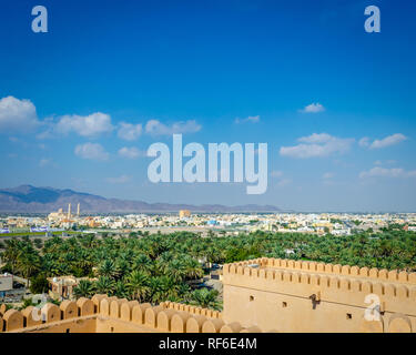 Oase in der Wüste, Barka Township und die Berge in der Ferne gesehen von der Terrasse der Nakhal Fort, Muscat, Oman. Stockfoto