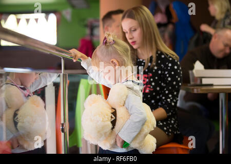 Urlaub in der Stadt. Kinder- Pavillon. trauriges kleines Mädchen mit einem Spielzeug auf dem Hintergrund von Mom Stockfoto