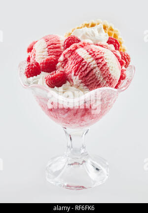 Leckere Vanille und Himbeere Eis Dessert im Glas Schale garniert mit frischen Beeren und einem Wafer über Weiß isoliert Stockfoto