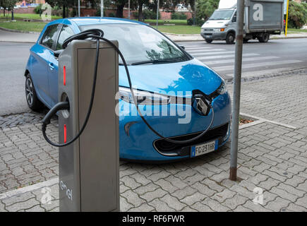 Renault aufladen durch Kabel in Steckdose hinter dem Fahrzeug vorne Logo auf Enel x Ladestation in Ostia verbunden, ein Stadtteil von Rom. Stockfoto