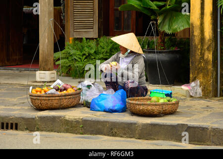 Hoi An, Vietnam - 20. Dezember 2017. Einem Straßenhändler bereitet Obst während der Wartezeit für die Kunden auf eine Straße in der historischen UNESCO Vietnamesisch Stockfoto