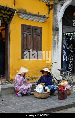 Hoi An, Vietnam - 20. Dezember 2017. Straßenhändler Chat während der Zubereitung von Mahlzeiten für die Kunden auf eine Straße in der historischen UNESCO vietnamesische Stadt Stockfoto
