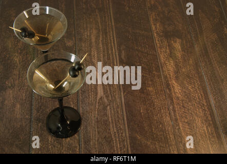 Zwei volle Martini Gläser mit zwei Oliven auf einem Zahnstocher, stand auf einem hölzernen Tisch. Close-up. Stockfoto