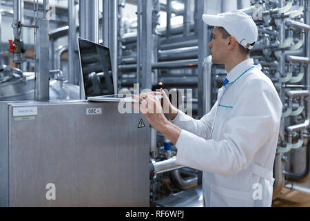 Techniker mit einem Laptop in der Hand an der Milchfabrik Stockfoto